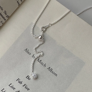 Minimalist S925 sterling silver chain necklace with a round zircon pendant on a vintage book