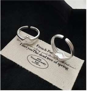 Detail view of two S925 sterling silver heart rings with matte finish and adjustable bands