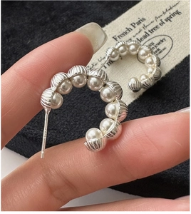 Close-up of S925 sterling silver C-shaped earrings with elegant white pearls on black cushion
