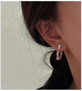 Detailed view of silver minimalist curved hook earrings with liquid metal texture on ear