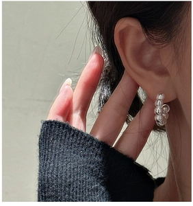 Detail of S925 sterling silver hoop earrings with textured beads on ear