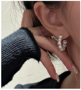 Detail of S925 silver C-shape twisted earrings with a glossy white pearl on model