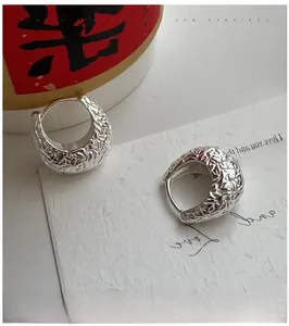 Macro detail of textured sterling silver hoop earrings with a hammered metal surface