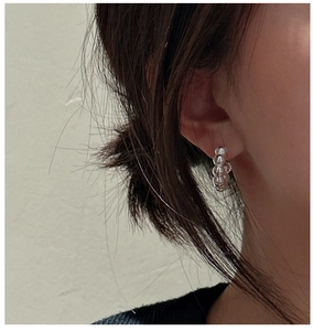 Detailed view of textured sterling silver hoop earrings worn by a model in soft light