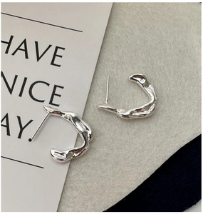 Detail of silver S925 earrings with irregular organic texture and minimalist C-shape