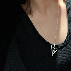 Elegant S925 sterling silver knotted heart necklace on black knit sweater