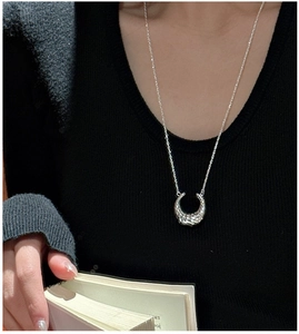 Dettaglio della collana in argento S925 con pendente a cornetto e trama martellata