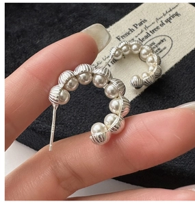 Macro shot of S925 sterling silver stamp on vintage shell-style pearl hoop earrings