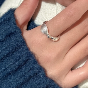 S925 sterling silver bow ring with brushed and polished texture on blue sweater background