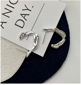 Macro shot of S925 sterling silver C-shaped earrings with irregular lava texture finish