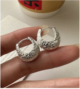 Macro shot of silver hoop earrings featuring a unique hammered texture and chunky design