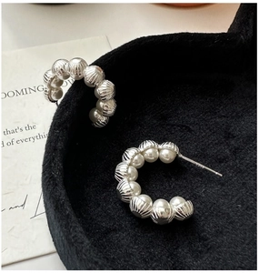 Macro view of S925 sterling silver stamp on C-shaped pearl earrings with ribbed texture