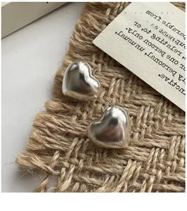 Macro shot of silver heart earrings with smooth polished finish on a neutral backdrop