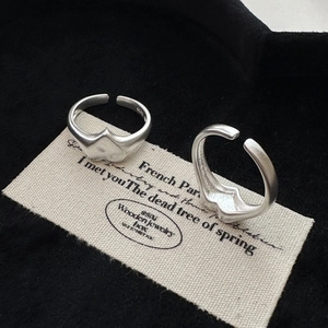 Minimalist S925 sterling silver matte rings with irregular wave design on canvas backdrop