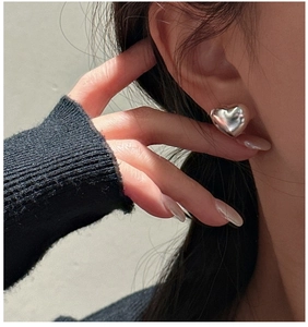 Close-up of minimalist S925 sterling silver hollow heart stud earring worn by model