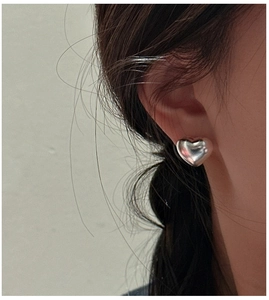 Close-up of S925 sterling silver hollow heart stud earrings worn by a model
