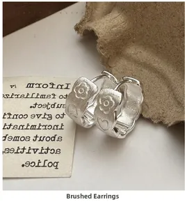Close-up of S925 sterling silver hoop earrings with brushed flower and heart relief