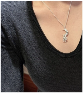 Close-up of S925 silver moon and star pendant necklace worn on a black knit sweater