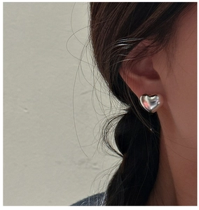 Close-up of 3D polished silver heart stud earring worn on ear with high mirror finish