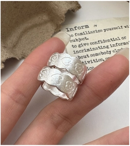 Close-up of S925 sterling silver brushed flower ring with engraved heart patterns