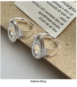 Detail shot of two S925 silver cutout rings with sunburst engraving on cardboard background
