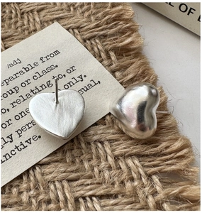 Detailed macro shot of 3D hollow heart silver studs with a brushed matte texture