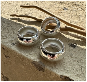 Close-up of three polished S925 sterling silver chunky rings on natural stone