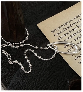 Macro shot of retro S925 silver beaded necklace with hollow teardrop pendant on wood