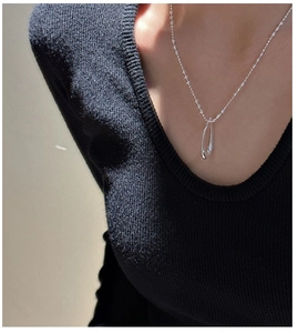 Detail of silver S925 minimalist water drop pendant on a beaded chain necklace