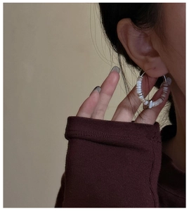 Side view of white and champagne beaded hoop earrings worn by a model for a vintage look