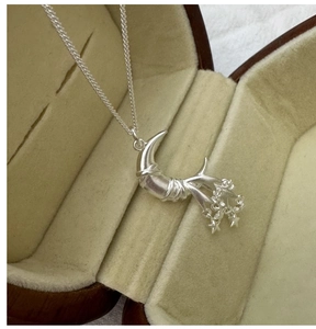 Detail of S925 sterling silver star and moon pendant inside a brown wooden jewelry box