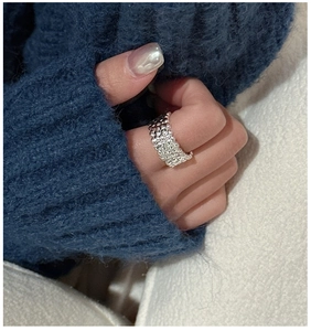 Detail view of silver textured wide ring with lava-like molten surface on finger