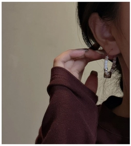 Detail of S925 silver hoop earring with white beads and brown accent on model