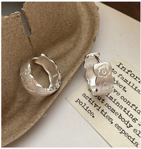 Macro shot of S925 silver hoop earrings with matte finish, flower and heart relief