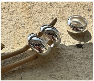 Close-up of three polished S925 silver thick round rings displayed on a dry branch