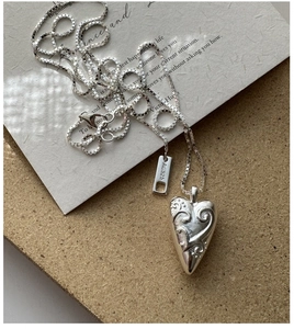Macro detail of S925 sterling silver heart pendant with vintage relief on box chain