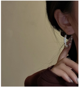 Detail view of vintage beaded hoop earrings with white and brown beads on a model
