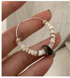 Close-up of S925 silver hoop earrings with white shell beads and ethnic wood accents