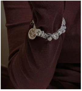 Detail of beaded bracelet with clear crystal beads and engraved LOVE metal charm pendant