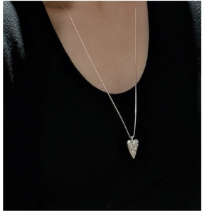 Detailed view of vintage S925 silver heart necklace with ornate engraving on a model