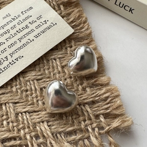 S925 sterling silver hollow heart earrings with polished finish on a natural woven mat