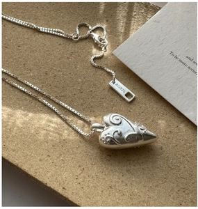 Detailed close-up of S925 sterling silver heart pendant with vintage floral engravings