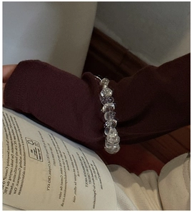 Macro shot of irregular clear crystal beaded bracelet on a brown knitted sweater cuff
