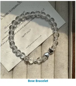 Macro view of white crystal bead bracelet featuring a silver bow tie accent charm