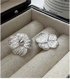 Macro shot of S925 silver flower stud earrings with brushed texture in a jewelry box