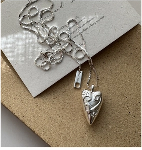Close-up of S925 sterling silver heart pendant with vintage scroll texture and box chain