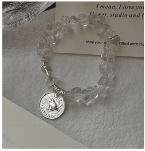 Macro view of S925 silver bird coin pendant on a beaded white crystal bracelet