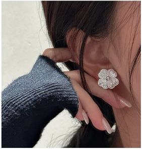 Macro detail of silver floral earring with white shell petals and textured metal stamen