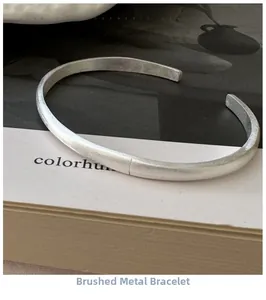 Detailed close-up of a brushed silver open bangle with a minimalist matte finish