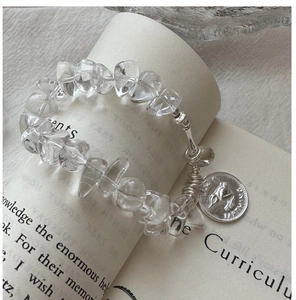 Macro shot of S925 silver beaded bracelet with clear crystals and bird coin pendant